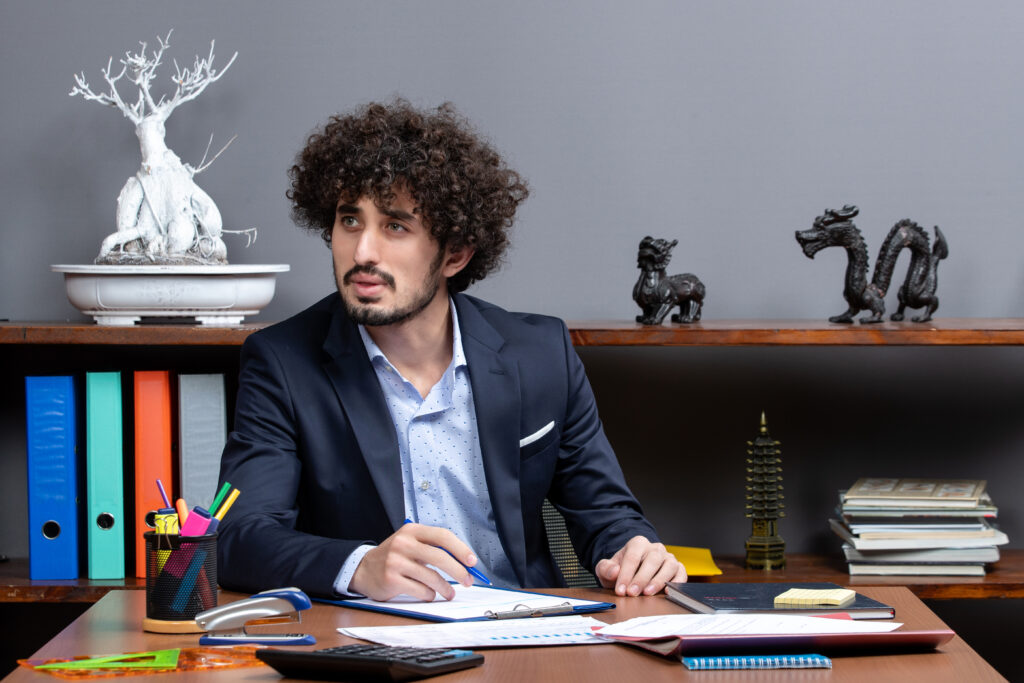 front-view-young-businessman-suit-sitting-desk-office